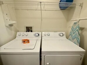 A laundry area with two white washing machines, a metal drying rack, and a small window. - Waterfront 2BR Condo w/ Pool + Resort Access (Palm Coast)