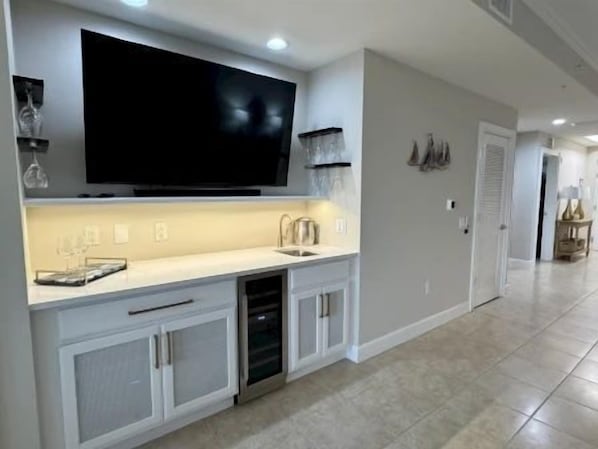 A modern kitchen with a flat-screen TV, built-in dishwasher, and a sink. - Waterway View 2BR Condo | Pool & Resort Access (Palm Coast)