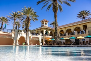 A hotel with a pool, palm trees, and outdoor seating with umbrellas. - Waterway View 2BR Condo | Pool & Resort Access (Palm Coast)