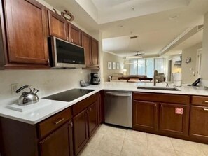 A kitchen with wooden cabinets, a stainless steel sink, and a dishwasher. - Waterway View 2BR Condo | Pool & Resort Access (Palm Coast)