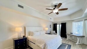 A bedroom with a bed, bedside tables, a ceiling fan, and a window with curtains. - Pool-View 2BR Condo w/ Balcony + Resort Access (Palm Coast)