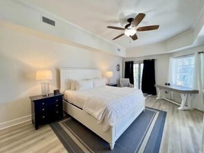 A bedroom with a bed, bedside tables, a ceiling fan, and a window with curtains. - Pool-View 2BR Condo w/ Balcony + Resort Access (Palm Coast)
