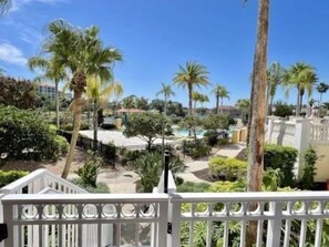 A resort with palm trees, a pool, and a fenced area. - Poolside 2BR Condo w/ Hammock Beach Resort Access (Palm Coast)