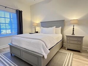 A bedroom with a bed, nightstands, and a window with curtains. - Poolside 2BR Condo w/ Hammock Beach Resort Access (Palm Coast)