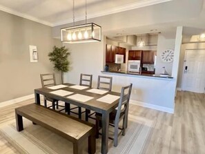 A dining area with a table and chairs, a bench, and a hanging light fixture. - Poolside 2BR Condo w/ Hammock Beach Resort Access (Palm Coast)