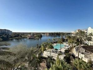 A resort with a pool, palm trees, and a river view. - Waterfront 2BR Condo | Hammock Beach Resort Access (Palm Coast)
