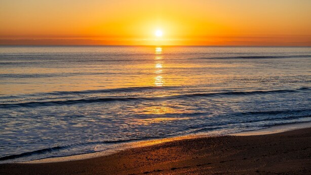 Una playa con olas y un atardecer.