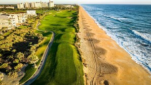 A coastal golf course with a beachfront view, surrounded by residential buildings. - Ocean-View 3BR Condo w/ Pools | Resort Access (Palm Coast)