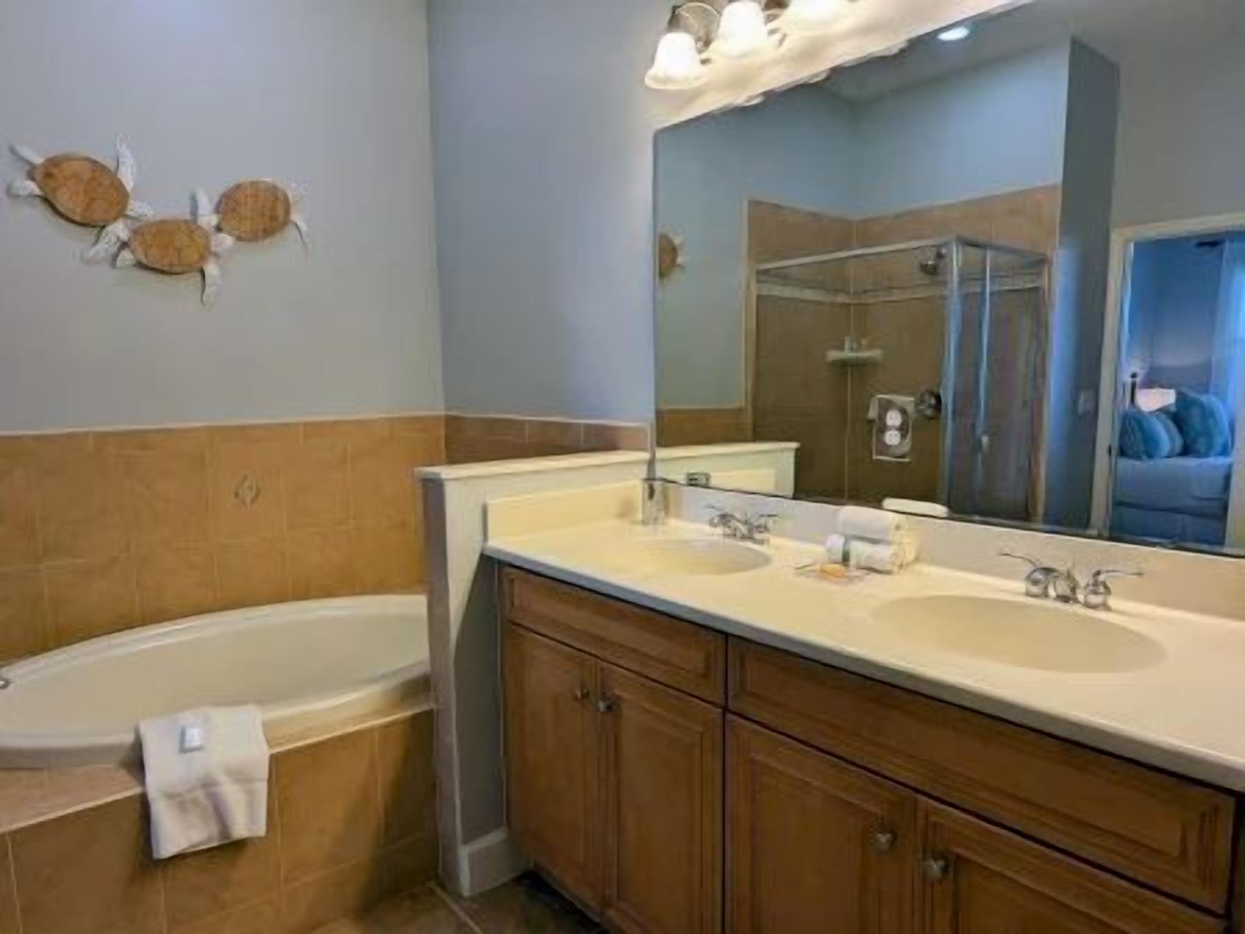 A bathroom with a bathtub, two sinks, a large mirror, and a towel rack.