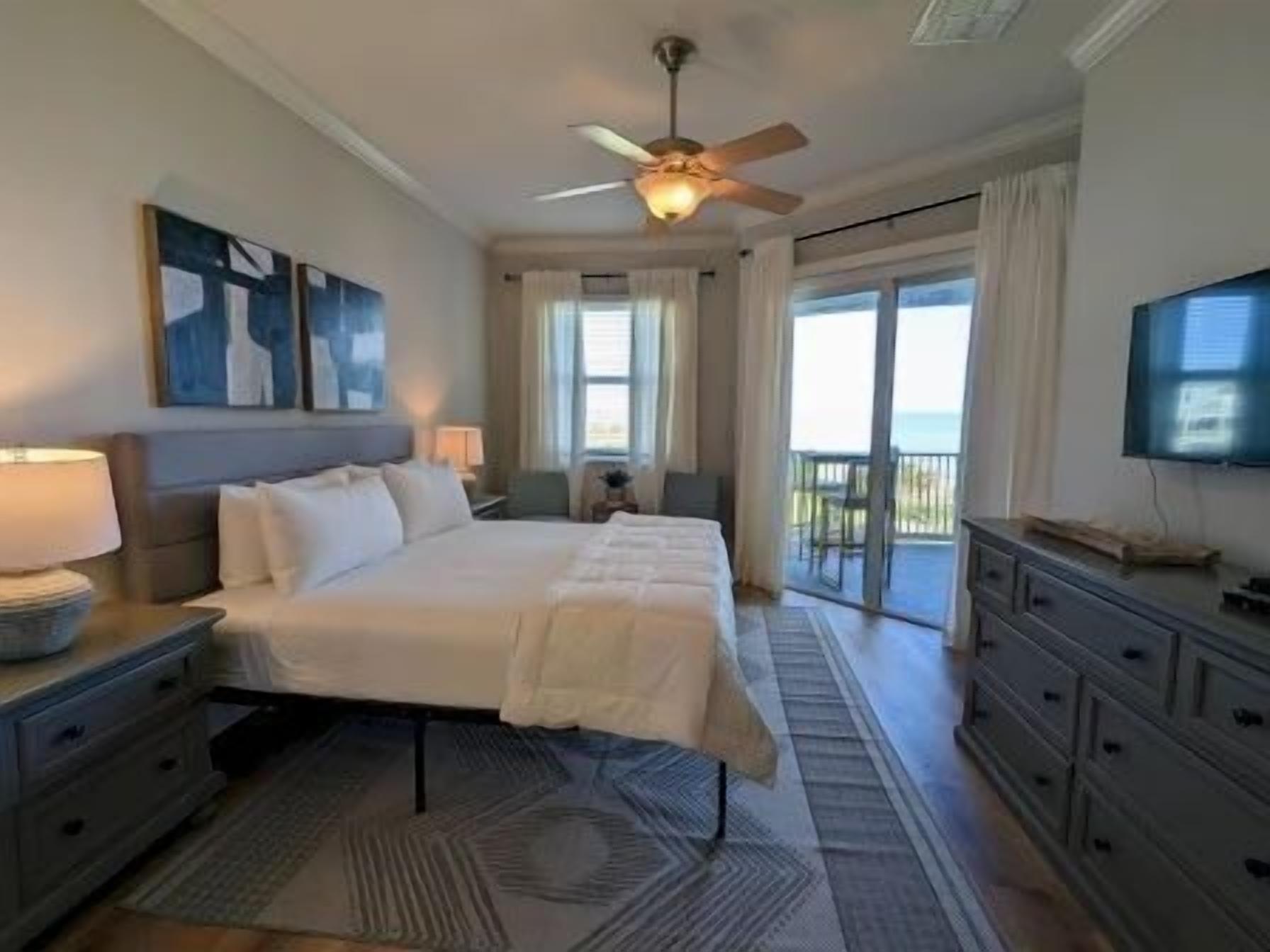 A bedroom with a bed, nightstands, a dresser, a ceiling fan, and a TV.