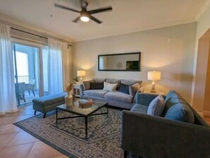 Uma sala de estar com sofá, mesa de centro e ventilador de teto.