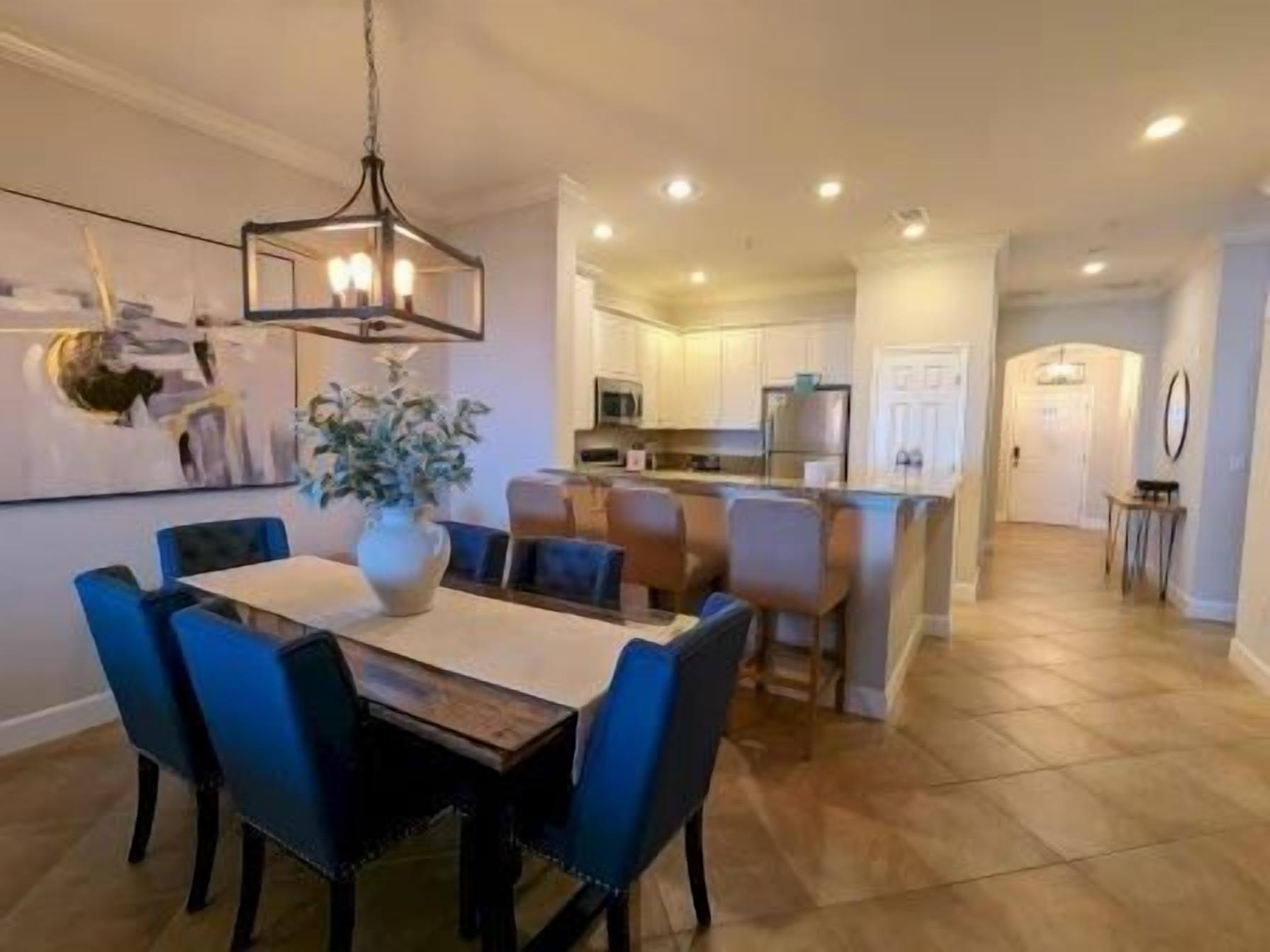 A dining area with a table, chairs, and a hanging light fixture.