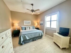 Un dormitorio con cama, cómoda, mesita de noche y ventilador de techo.