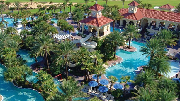 Um resort com várias piscinas, palmeiras e vista para o oceano.