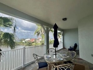 A covered outdoor area with a table and chairs, a grill, and a view of a body of water and buildings. - Lakeside 3BR Condo w/ Hammock Beach Resort Access (Palm Coast)