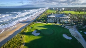 Ein Küsten-Golfplatz mit einem großen Gebäude, vermutlich eine Klubhaus, direkt neben dem Strand.