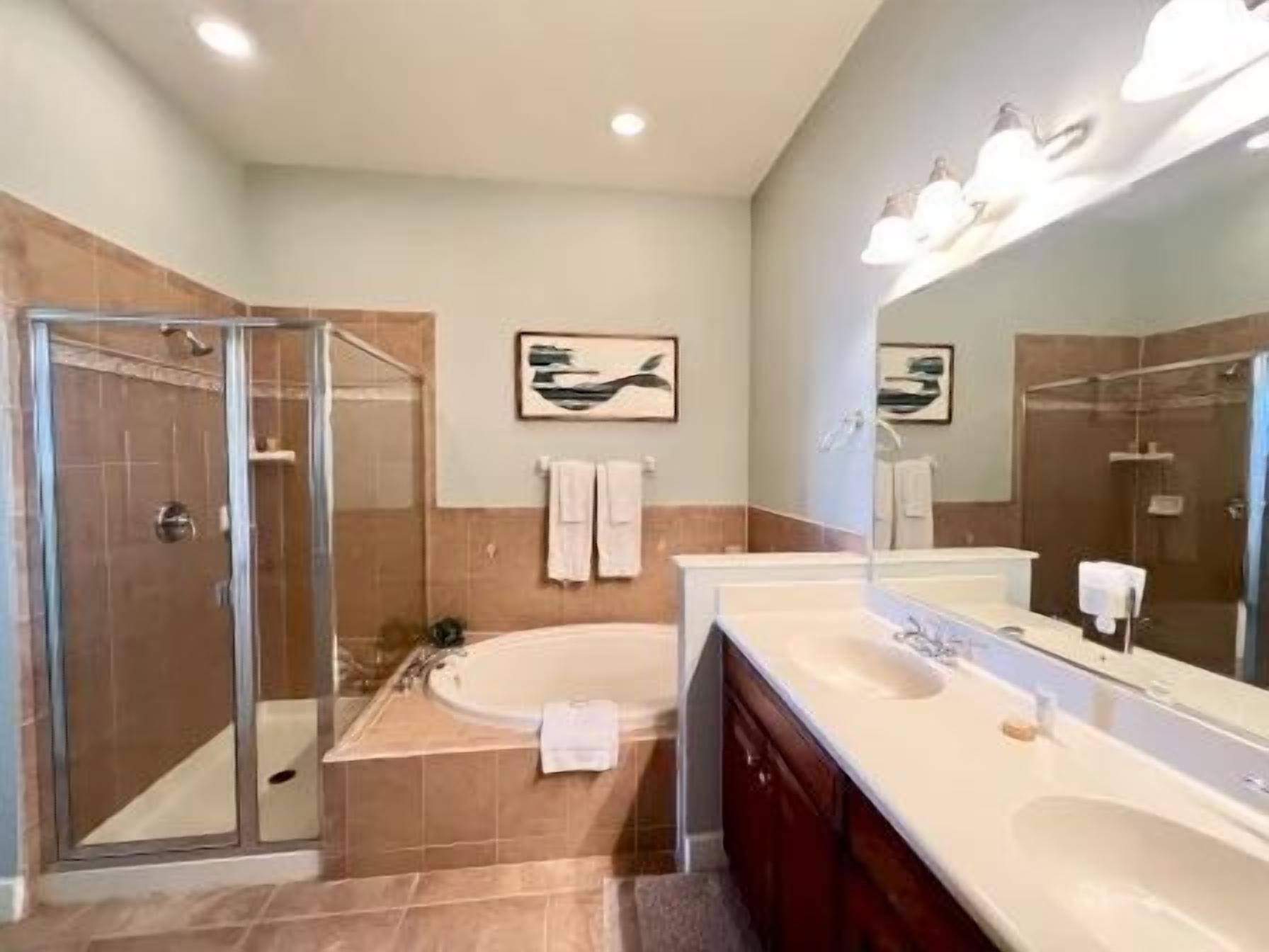 Un baño moderno con cabina de ducha de vidrio, una bañera y un espejo grande.