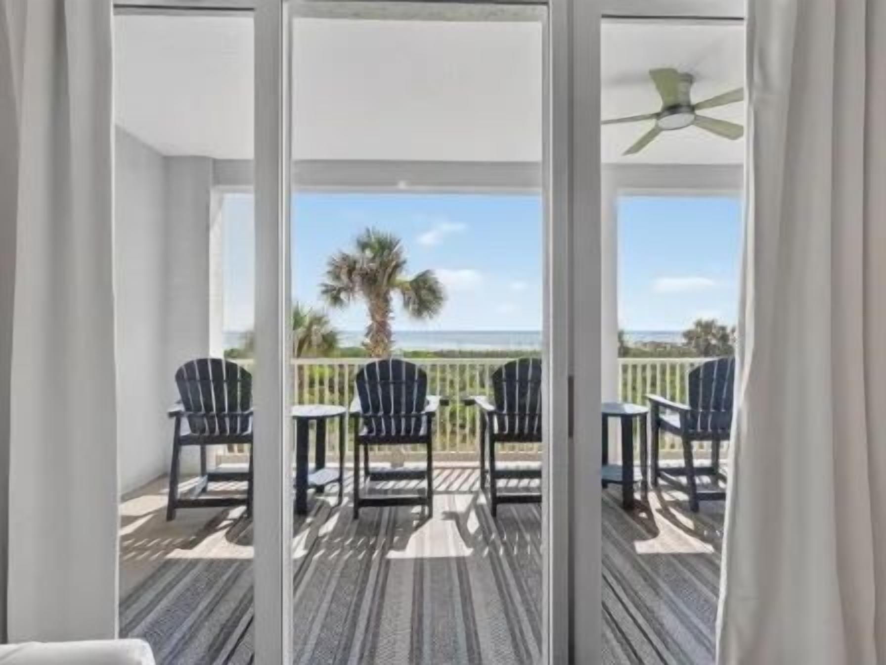Ein Balkon mit Blick auf den Strand, ausgestattet mit Stühlen und einem Tisch.