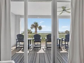 Ein Balkon mit Blick auf den Strand, ausgestattet mit Stühlen und einem Tisch.