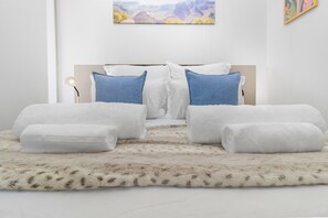 A bedroom with a bed, two pillows, a fluffy rug, and a painting on the wall. - One Rosebank 151 - One Bedroom Apartment, Sleeps 2 (Johannesburg)