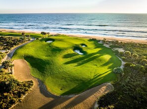A golf course with a sandy beach and ocean view. - Lake-View 11BR House | Heated Pool & Resort Access (Palm Coast)
