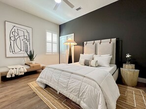 Ein Schlafzimmer mit einem großen Bett, einem Nachttisch, einer Lampe und einem Wandbild.