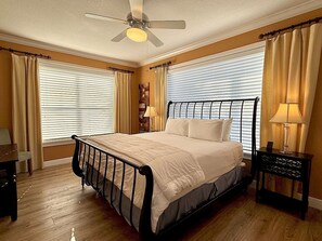 A bedroom with a bed, a nightstand, a lamp, a ceiling fan, and a window with blinds. - Luxe 4BR Home | Pool & Hammock Beach Resort Access (Palm Coast)