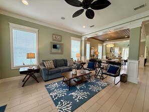 A spacious living room with a sofa, coffee table, and chairs, a dining area with a table and chairs, and a kitchen in the background. - Pet-Friendly Home w/ Hammock Beach Resort Access (Palm Coast)