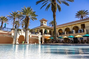A hotel with a pool, palm trees, and a Mediterranean-style building with arches and a bell tower. - Oceanview 5BR Home w/ Pool, Beach & Resort Access (Palm Coast)
