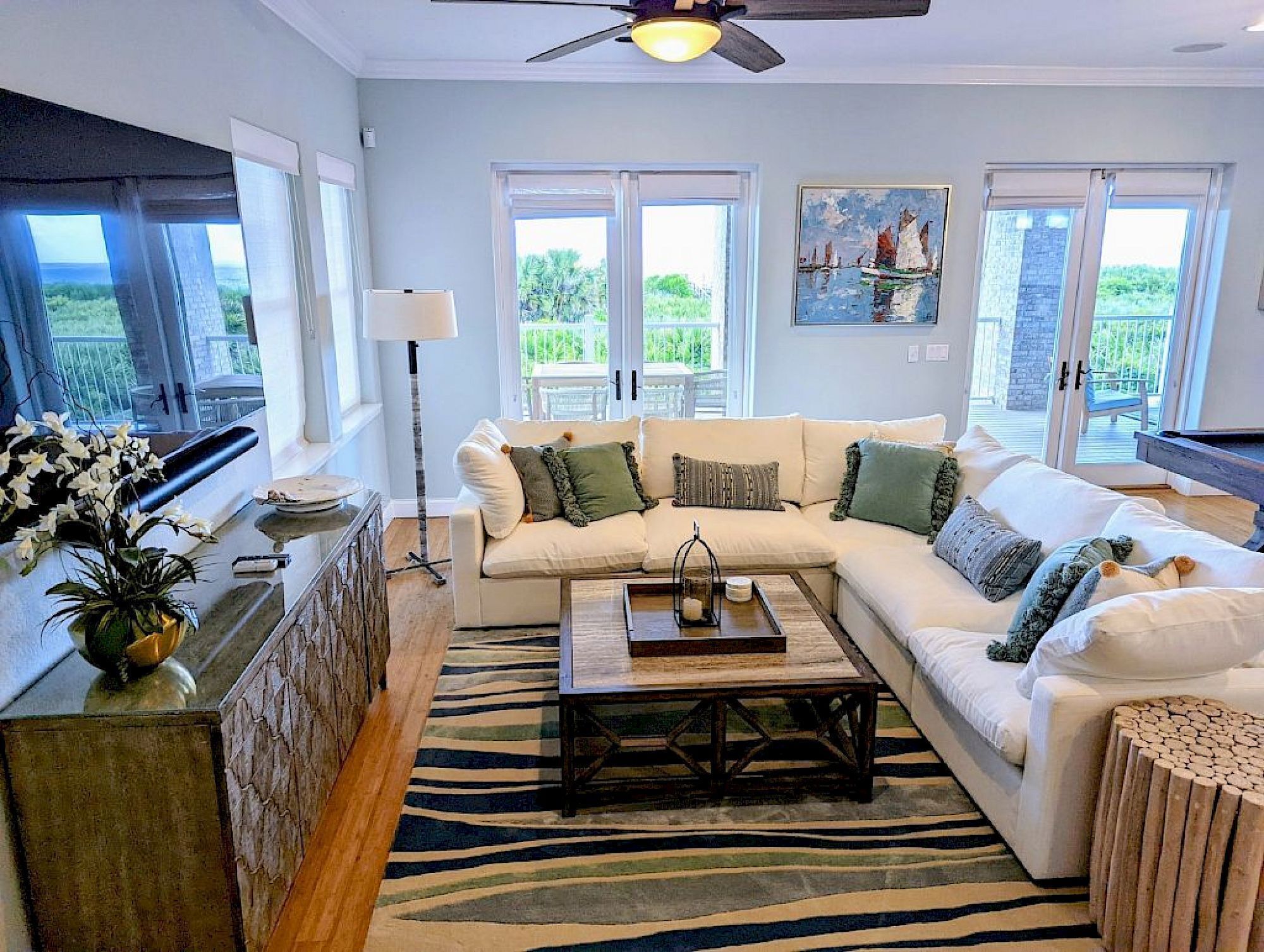 A living room with a sectional sofa, a coffee table, a zebra-pattern rug, and a view of the outdoors through large windows.