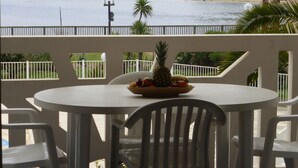 Un balcón con mesa y sillas, con vista a una playa y el agua.