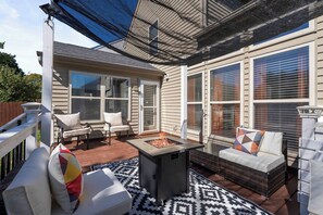 An outdoor patio with a fire feature, seating, and large windows. - Fire Table Deck · 9 Min to Easton · Sleeps 8 (Columbus)