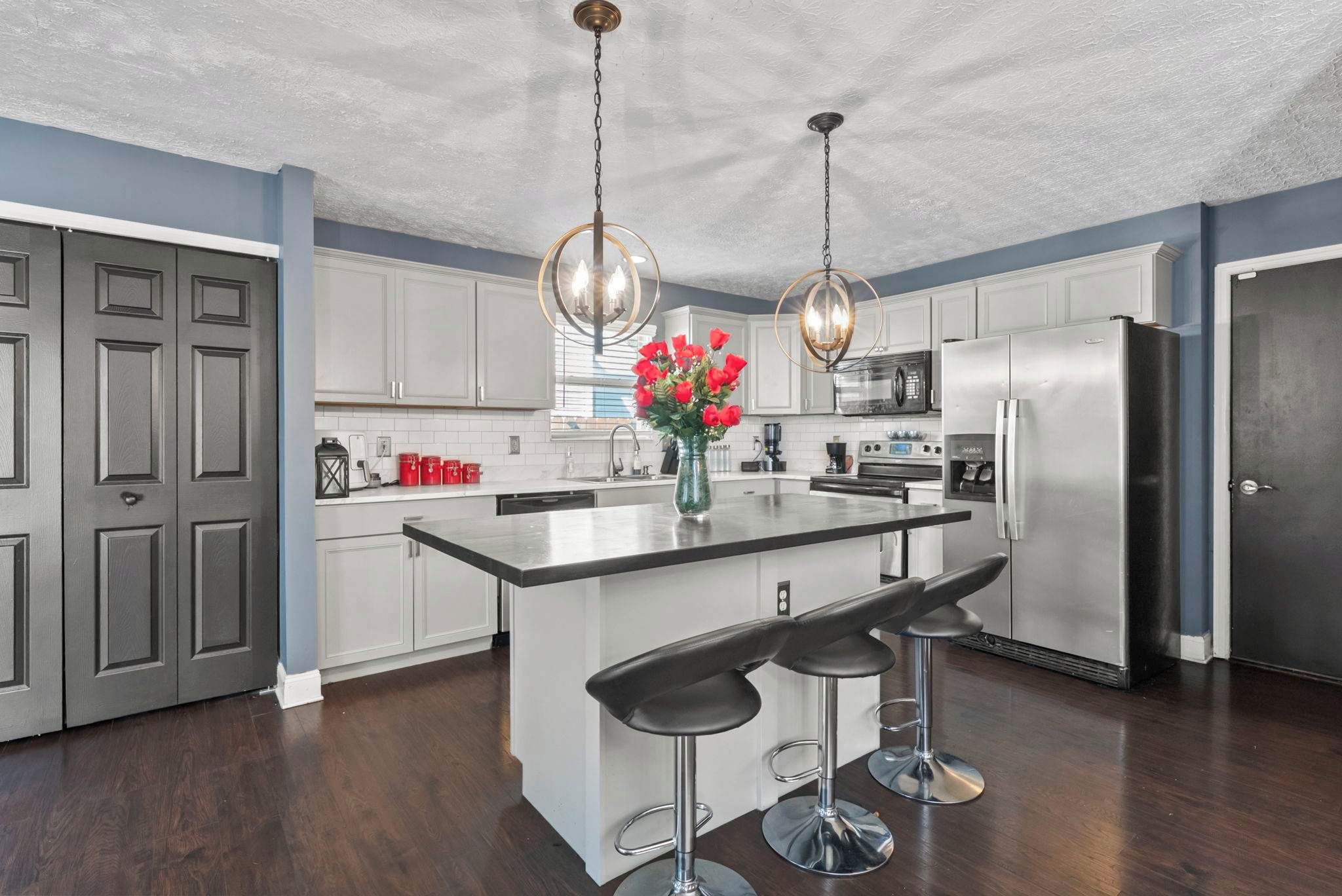 Una cocina moderna con una isla central, electrodomésticos de acero inoxidable y un jarrón decorativo con flores.