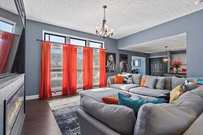 A modern living room with a grey sofa set, red curtains, and a fireplace. - Fire Table Deck · 9 Min to Easton · Sleeps 8 (Columbus)