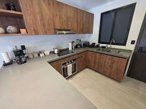 Eine moderne Küche mit Holzschränken, einem Einbauofen, einer Spüle und einer Kaffeemaschine.