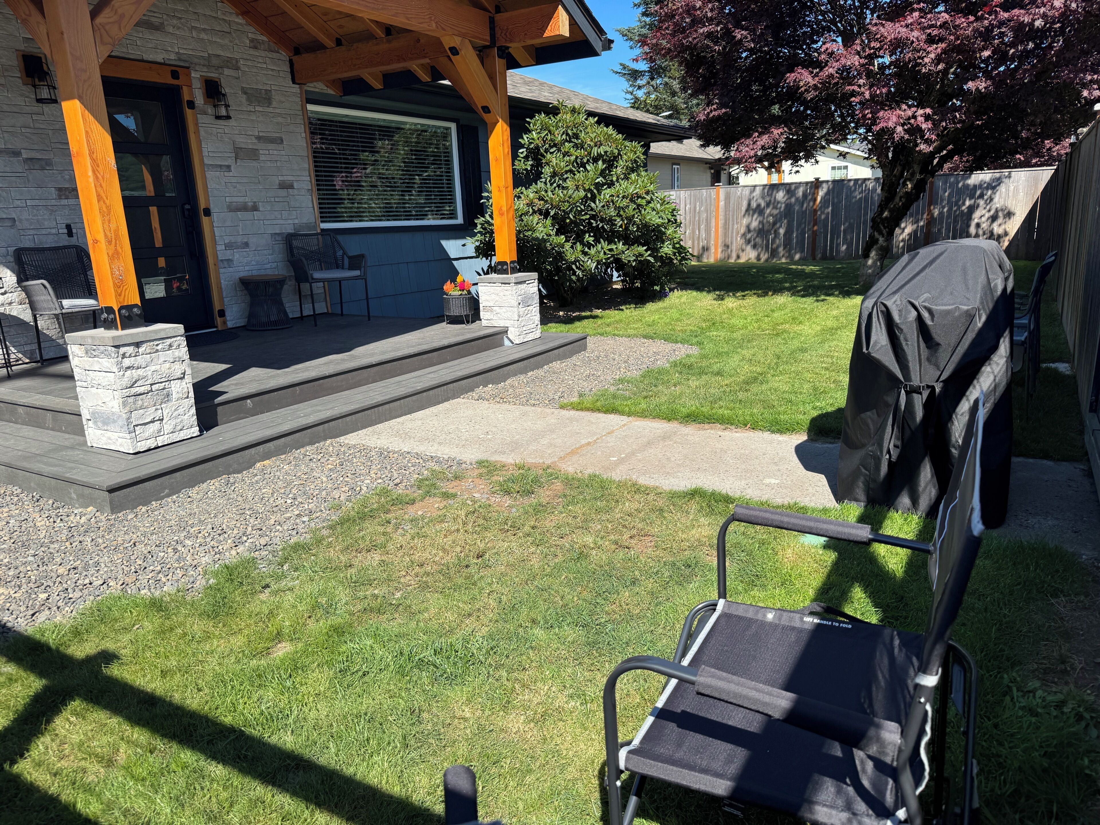 Une terrasse avec des meubles d’extérieur, un barbecue et un bac à fleurs en pierre.