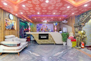 A reception area with a marble floor, a reception desk, a clock, and decorative elements including statues and floral arrangements. - Deluxe Skyline Haven (Barasat)