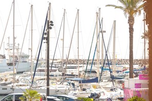 Un puerto deportivo con varias embarcaciones amarradas, una palmera y un edificio con un letrero.