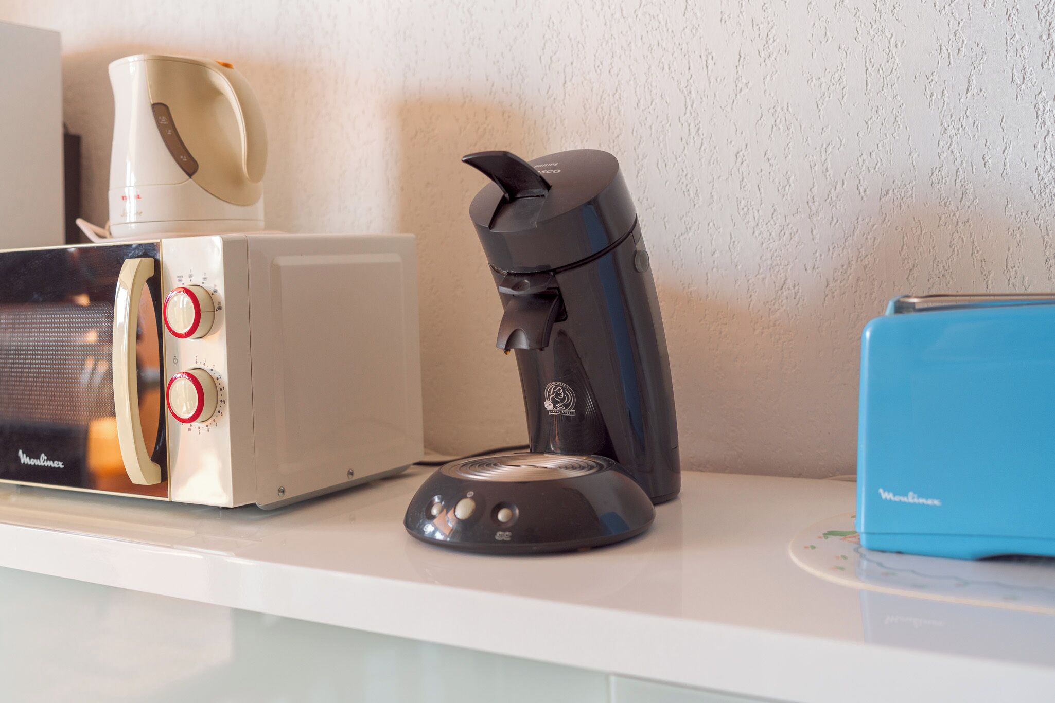 A kitchen counter with a toaster, a coffee maker, and a blue appliance.
