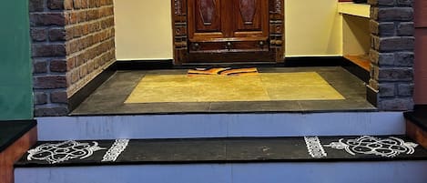 A wooden door with a decorative design, flanked by brick pillars, and a set of steps leading up to it.