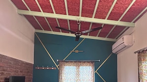 Ein Schlafzimmer mit Bett, Fernseher, Fenster und Deckenventilator.