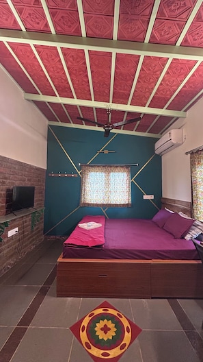 A bedroom with a bed, a TV, a window, and a ceiling fan.