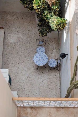 Une terrasse avec une table et des chaises, un pot de fleurs et un mur.