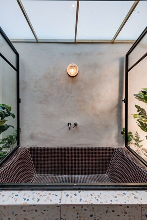 Un espace de détente avec un sol carrelé, un luminaire fixé au mur et deux robinets.