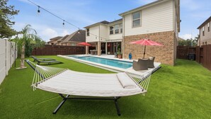 Un patio trasero con piscina, una hamaca y un área de patio.