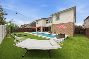 Ein Garten mit Schwimmbad, Hängematte und Terrassenbereich.