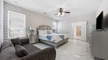 A bedroom with a bed, a nightstand, a lamp, a ceiling fan, a TV, and a wardrobe.