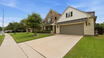 A residential street with houses, a driveway, and a sidewalk.