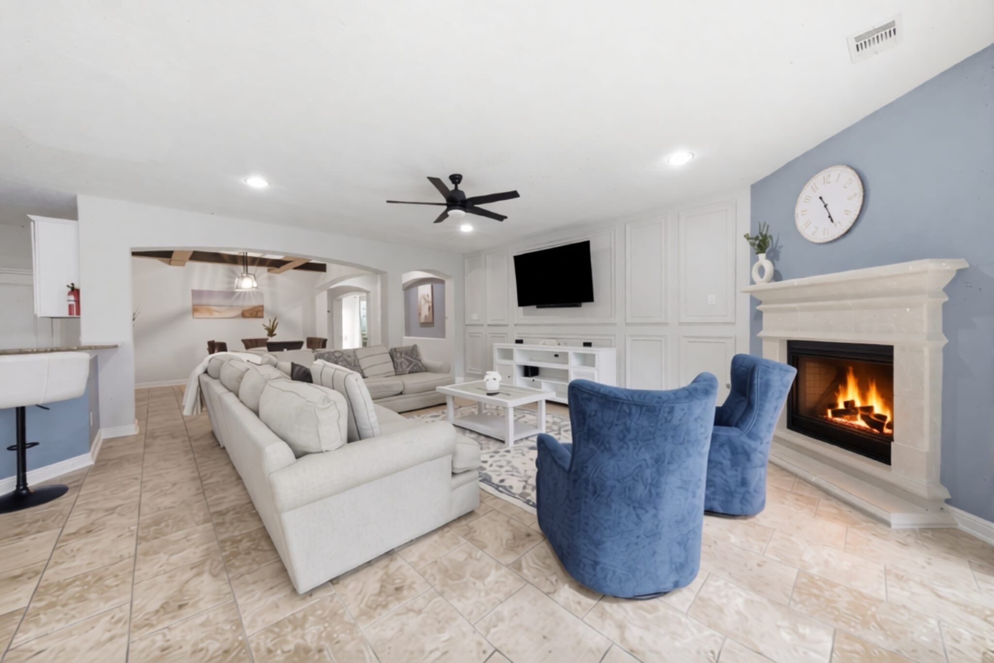 A modern living room with a fireplace, a television, and a ceiling fan.