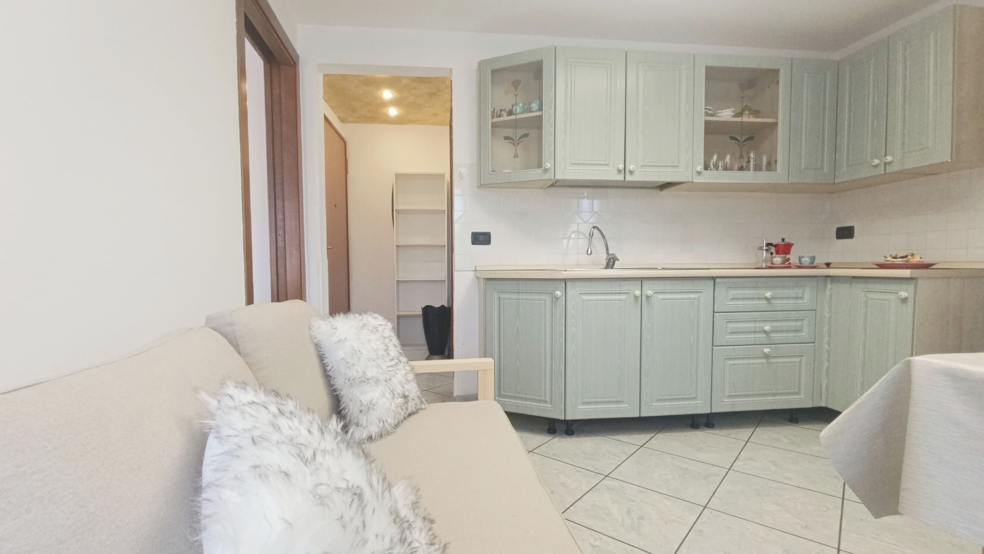 Una sala de estar con sofá y un comedor con cocina al fondo.